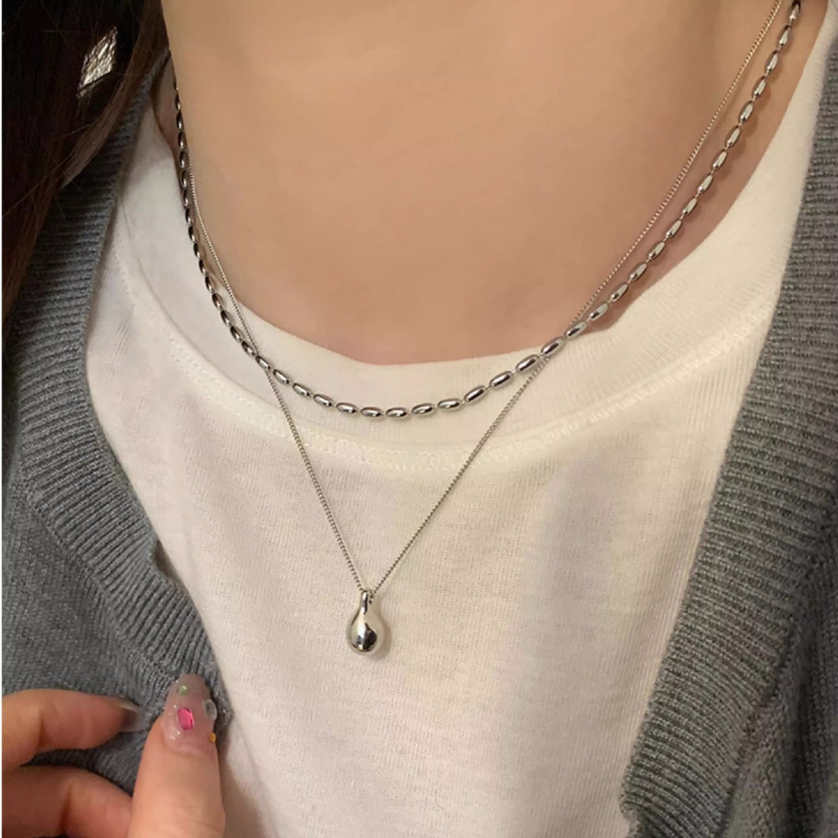 A minimalist silver double-layer necklace with a niche design for women, exuding a simple and elegant charm. It features a water drop pendant and a rice-grain collarbone chain full figure