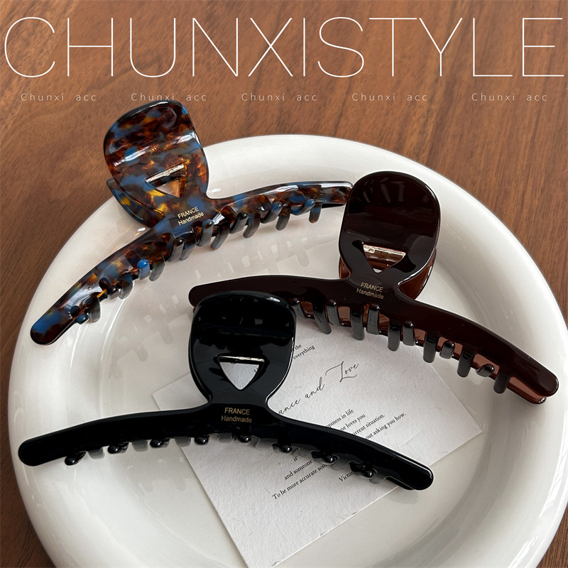 The large-sized acetate hair clip has a lot of volume and a retro style. It's a 13cm large-sized shark clip at the back of a woman's head details Picture