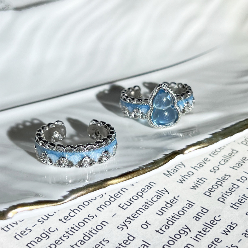 A simple and individual couple ring with a Chinese trend style, featuring a sea blue gradient enamel and a gourd-shaped opening. It has a lace trim full figure