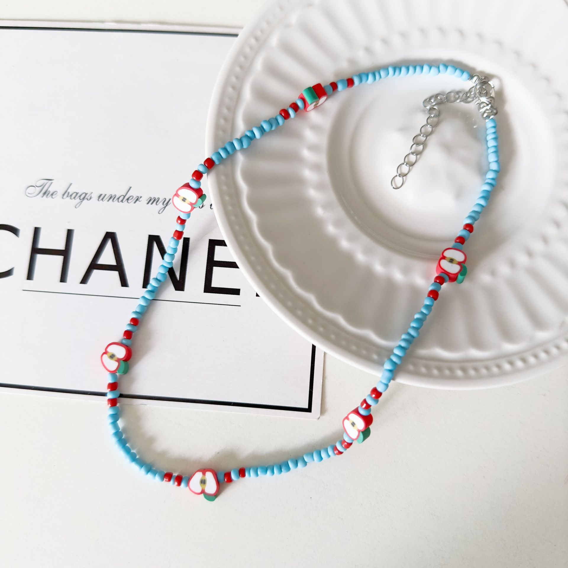 A fresh Japanese and Korean rice beaded soft clay apple necklace with a sweet and forest style, a niche design, and a collarbone chain for a young girl full figure