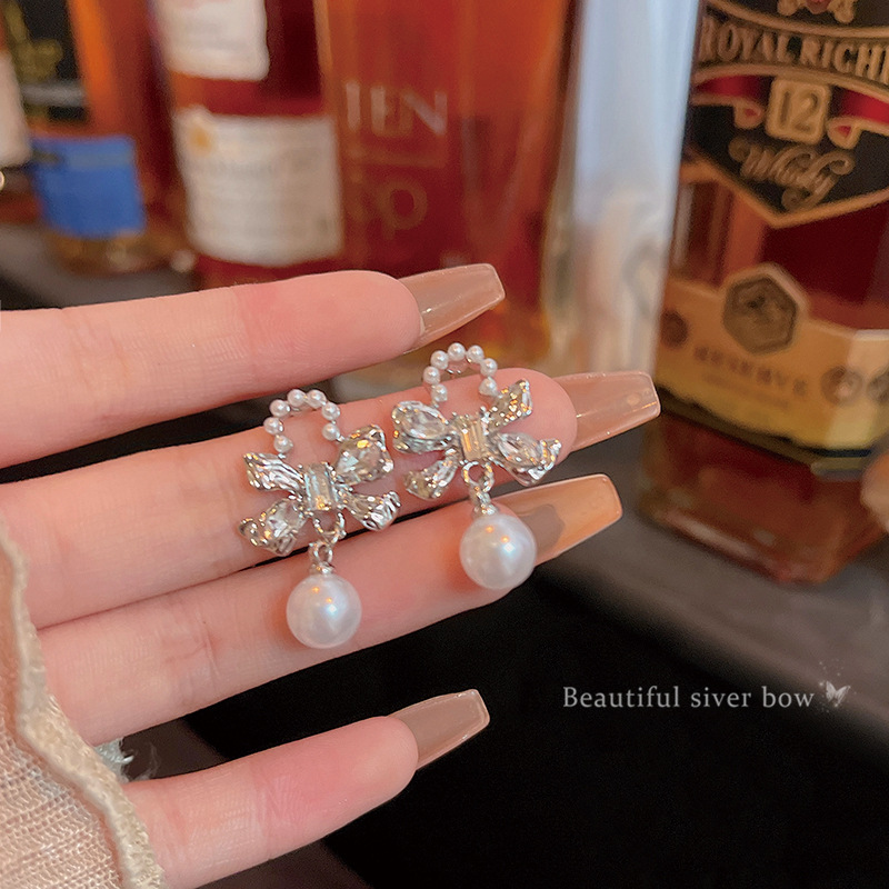 The Korean-style silver bow pearl earrings exude a sense of fashion and sophistication for women. They are versatile and exquisite zircon stud earrings, a best-selling accessory full figure