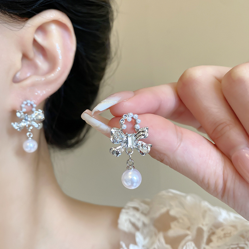 The Korean-style silver bow pearl earrings exude a sense of fashion and sophistication for women. They are versatile and exquisite zircon stud earrings, a best-selling accessory details Picture