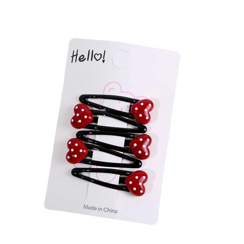 The little girl has a bangs on the side of her forehead with a red Ankela hair clip, a children's polka dot heart-shaped bb hair clip and a hair accessory Item Picture