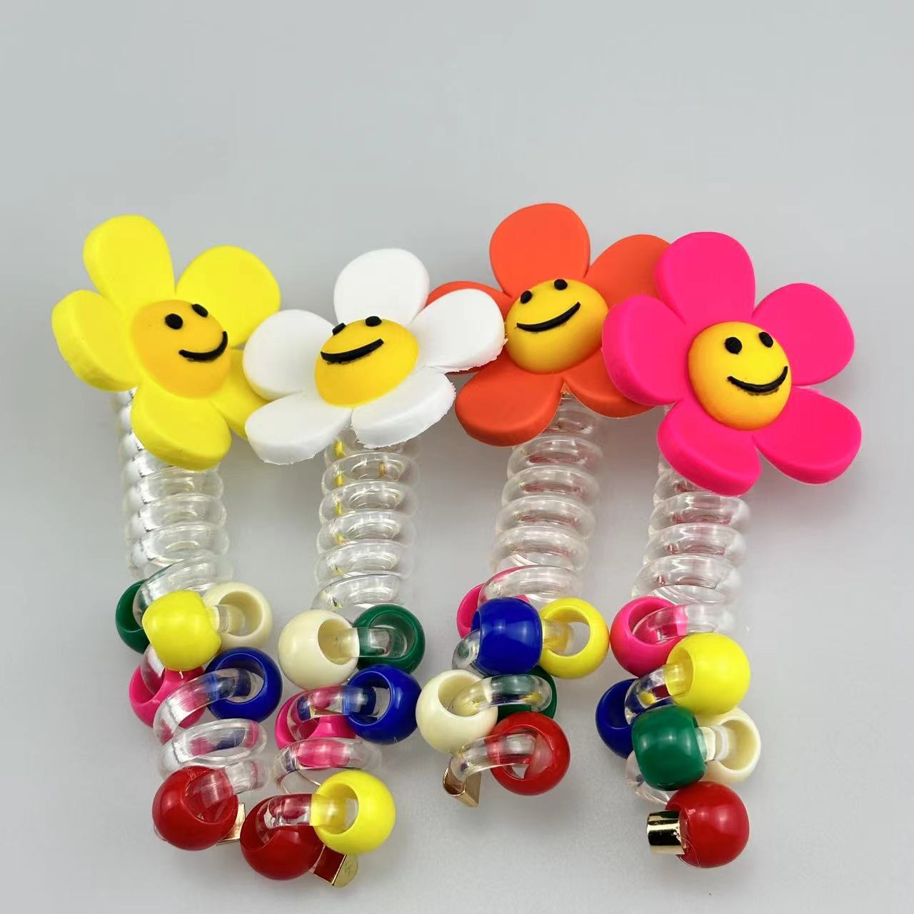 A girl's sunflower telephone line hair tie with a smiling face, a transparent ponytail braid, a hair braiding tool, and a beaded hair string accessory details Picture