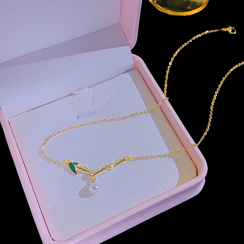 This is a genuine gold electroplated small bamboo joint titanium steel necklace with a fashionable and light luxury design. It features a pearl pendant and a collarbone chain, making it a versatile accessory Application Scenario