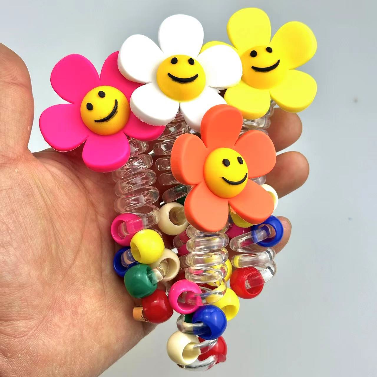 A girl's sunflower telephone line hair tie with a smiling face, a transparent ponytail braid, a hair braiding tool, and a beaded hair string accessory full figure