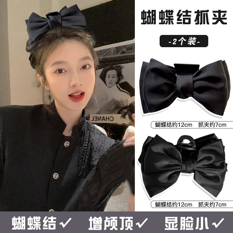 A black double-sided Korean-style large bow hair accessory with a hairpin on the back of a woman's head full figure