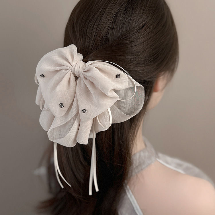 The elegant bow hair clip accentuates a woman's tall head. The ponytail hair clip exudes a sense of sophistication and grace. The half-tied hair is placed at the back of the head with a hair clip details Picture