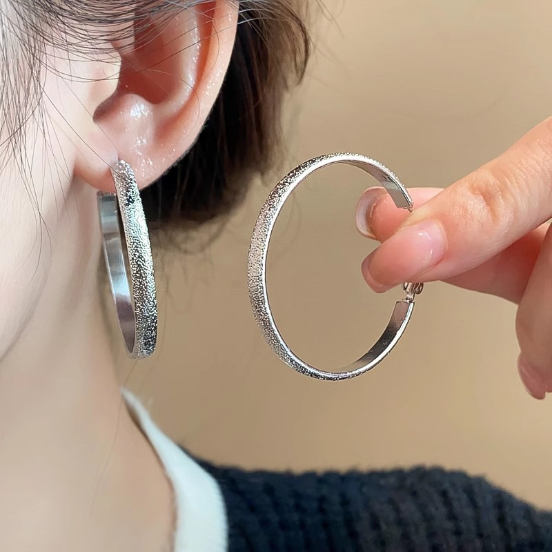 The light luxury matte silver large ear rings exude a feminine charm and a sense of sophistication. The fashionable and exaggerated ear studs are simple and niche design earrings full figure