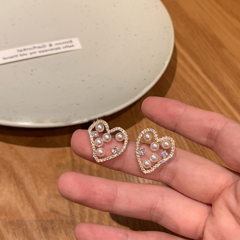 Wholesale of new autumn and winter heart-shaped hollowed-out pearl stud earrings for women, featuring a niche design sense, light luxury, individuality and versatility full figure