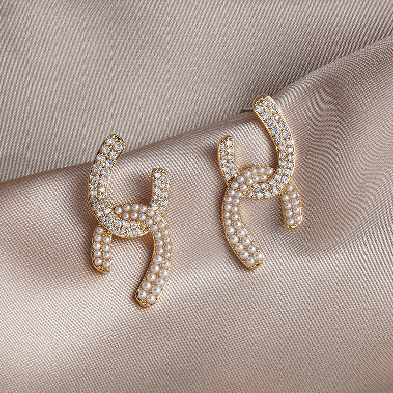 The S925 silver needle French design cross-geometric pearl stud earrings exude an elegant and refined charm. The small chanel-style earrings are sweet and fashionable full figure