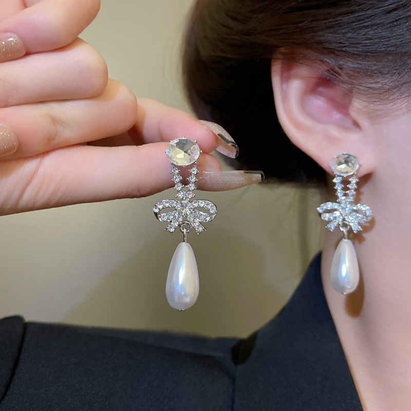 S925 Silver Needle Korean diamond-encrusted bow pearl Hundred-tower earrings, a fashionable, light luxury, individual and simple earpiece trend for women details Picture