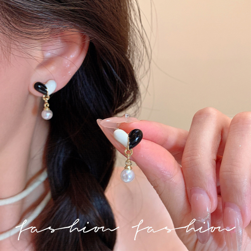 Black and white mixed-color heart-shaped pearl stud earrings exude a sense of sophistication, are versatile, and feature a niche design. They are a high-end, simple, and commuter style earpiece full figure