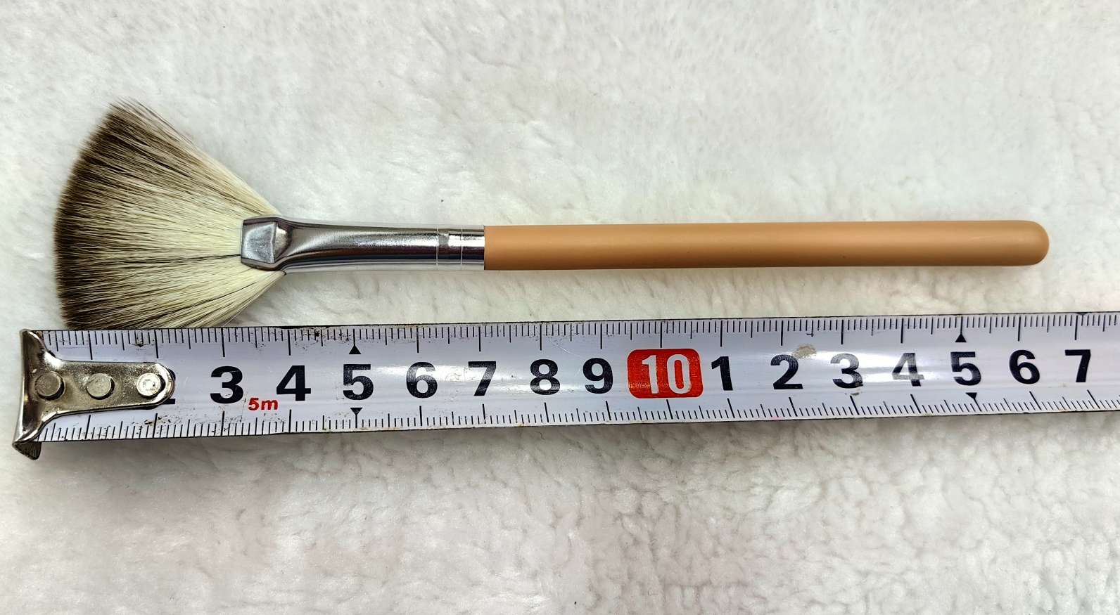 Fan brush in travel case next to skincare products