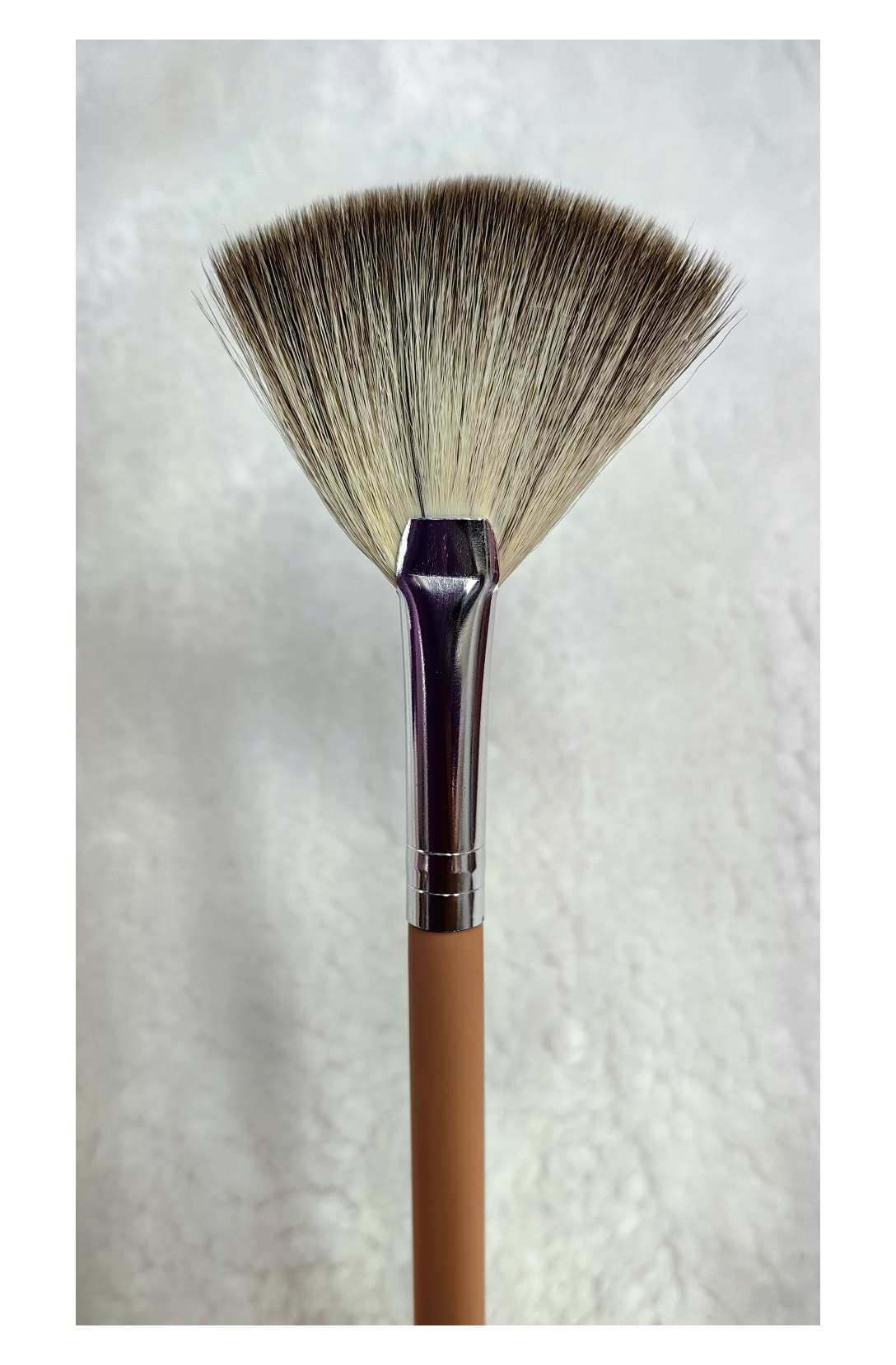 Close-up of fan-shaped brush applying serum to cheek