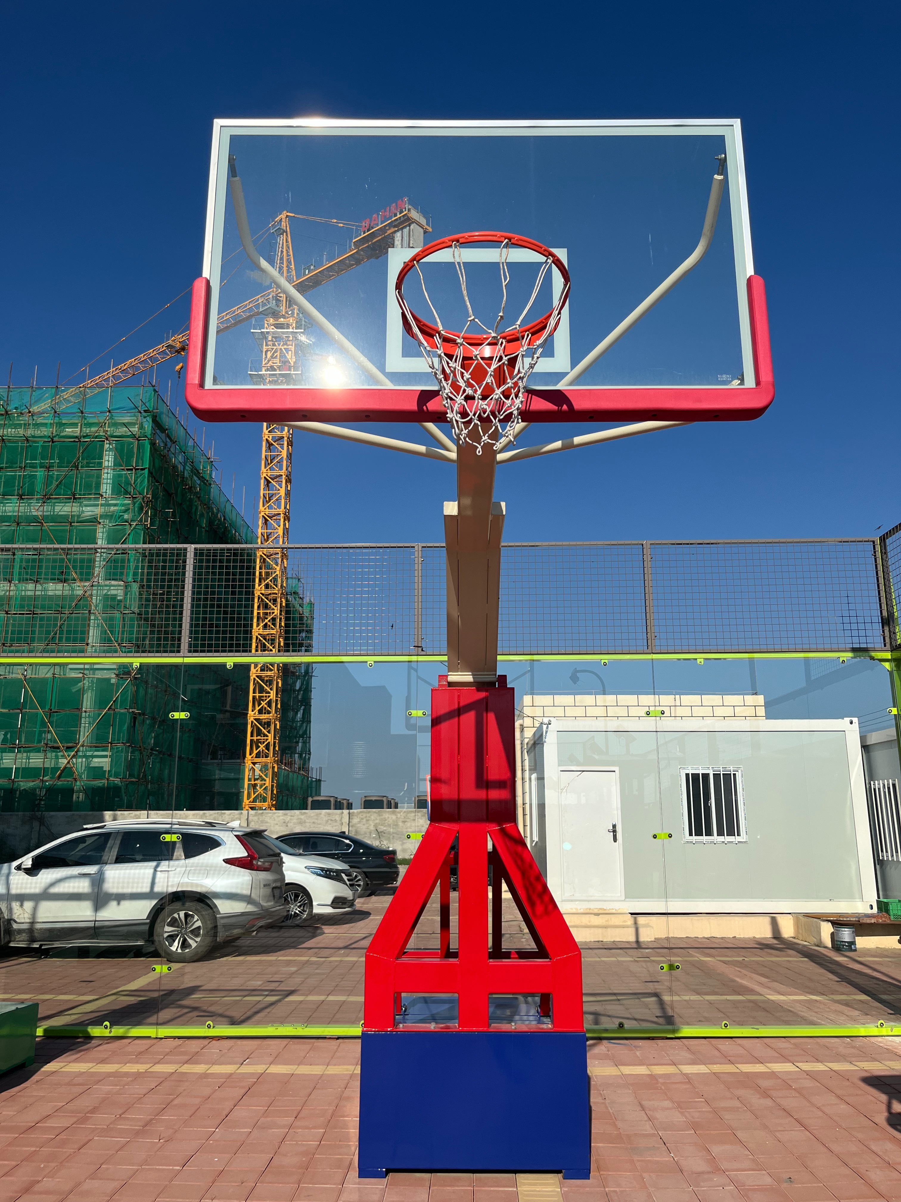 Portable basketball stand with wheels being moved across backyard