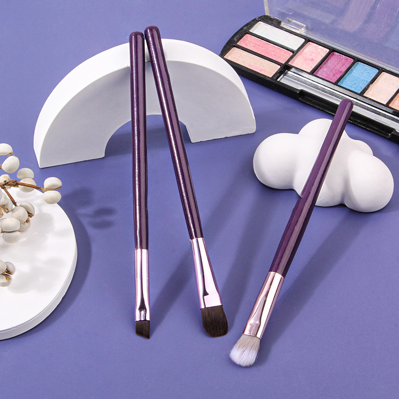 A set of 3 purple wooden-handled eye makeup brushes, including a soft-bristled eyeshadow brush, a smudging brush, a portable lip brush, and a "sleepy eye" refreshing style full figure