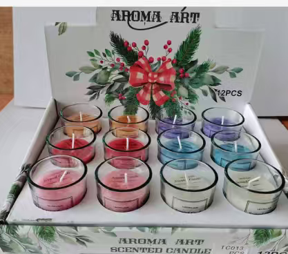 This is a box of 12 scented candles of the "AROMA ART" brand. The candles are placed in transparent glasses and come in a rich variety of colors, including pink, red, orange and purple