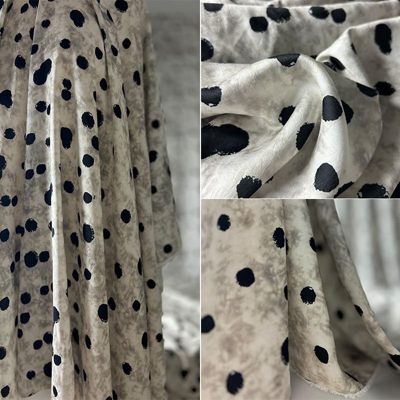This fabric features a soft and drape design with a stir-fried grey base, slightly wrinkled satin finish, and irregular large polka dot printed acetate fabric