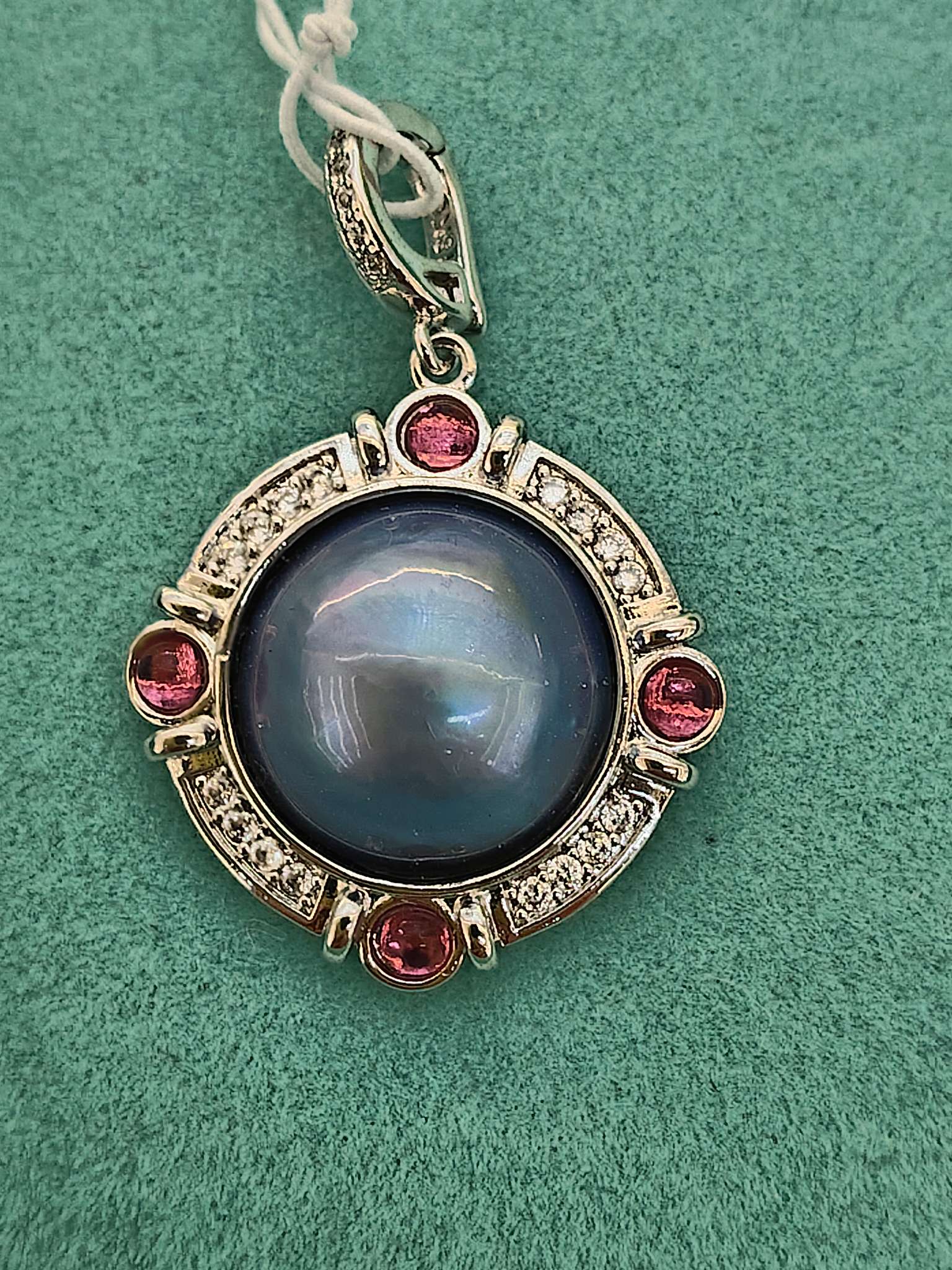 A small round blue pearl pendant set with red diamonds