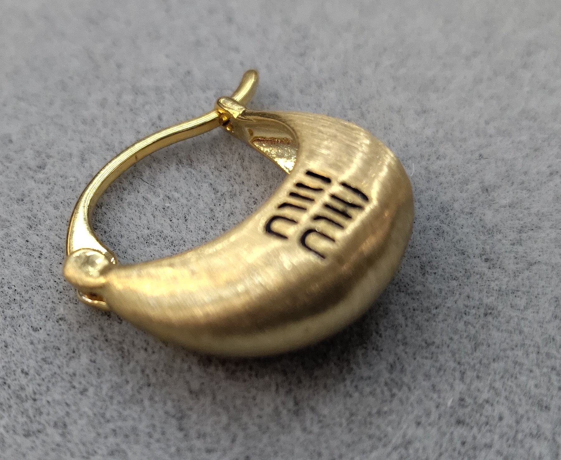 The new Waka Mi golden ear buckles are engraved with the English words "MIUMIU", and their simple design exudes a unique charm Specification image