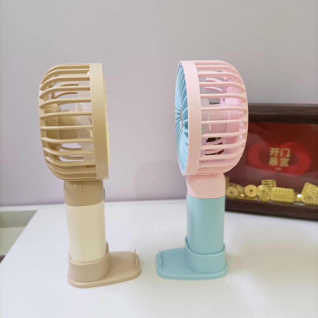 The new simple and mini handheld fan has a strong wind force and can be charged by USB. It is a portable desktop stand for outdoor students details Picture