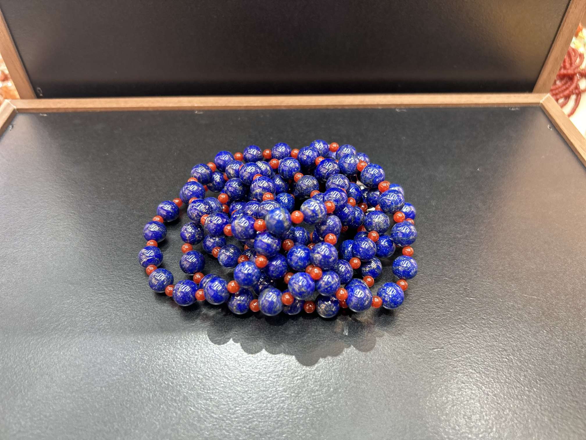 首饰这款青金石手串以浓郁宝蓝圆珠为主，颗颗质感醇厚，间杂艳红小珠做点缀，红蓝撞色鲜明亮眼，古典韵味十足，上手尽显沉稳大气