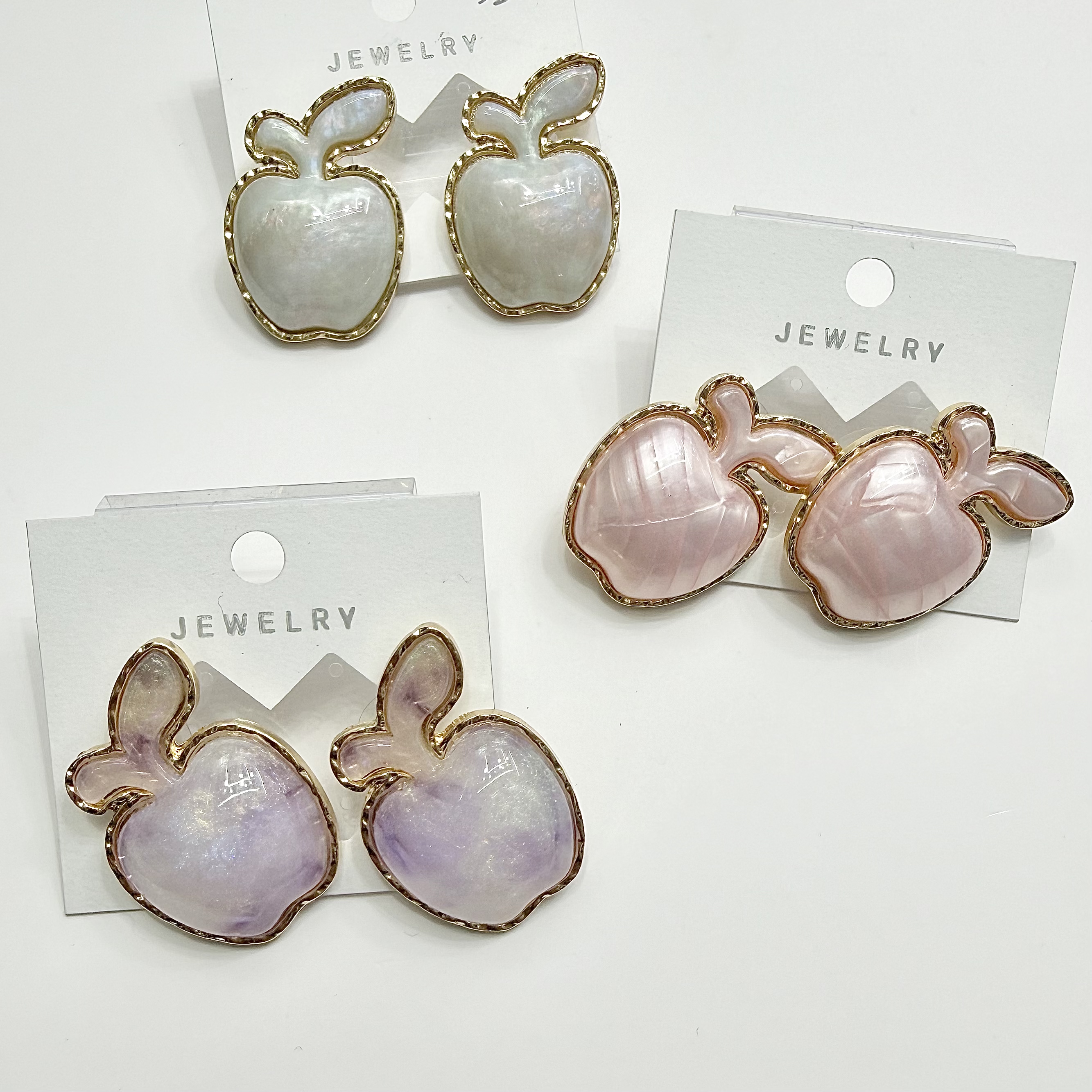 Three pairs of apple-shaped earrings with white, pink, purple and gold borders as JEWELRY accessories