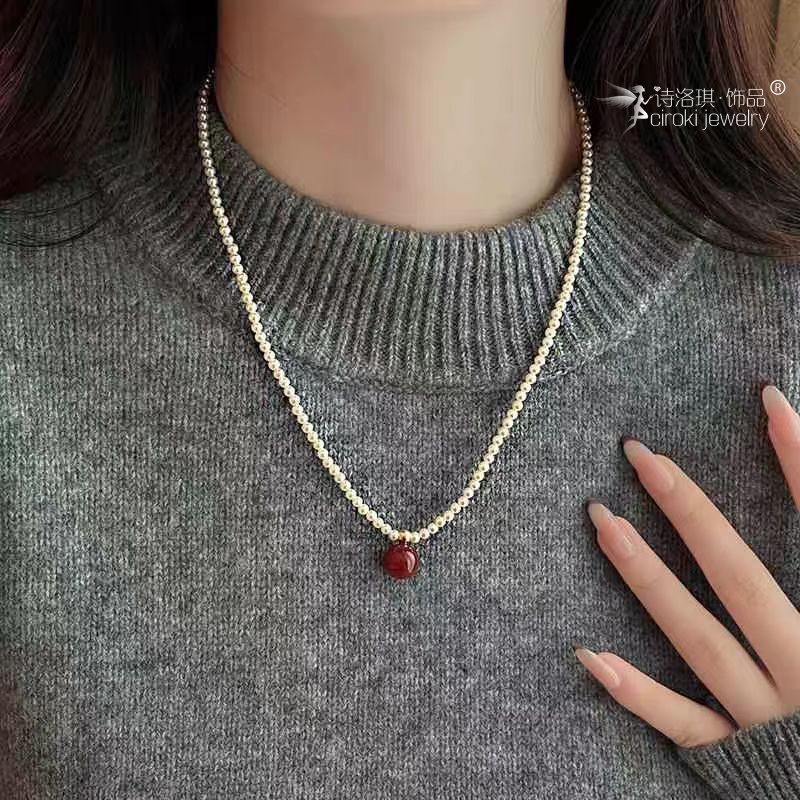 The Siloqi shielded red beaded pendant necklace for women's autumn and winter exudes a high-end, light luxury and niche charm. It's a new best-selling sweater chain