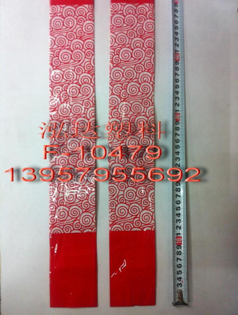 A red plastic scroll with white cloud patterns, pure red background and a ruler