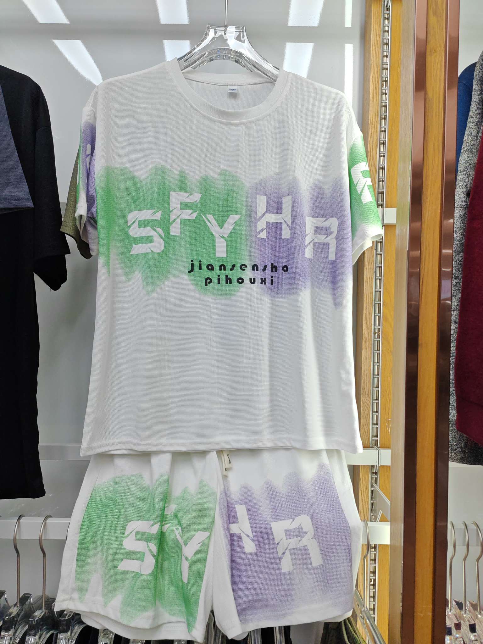 A white short-sleeved T-shirt with shorts set, featuring green and purple watercolor and SFYHR printed clothing detail image 1