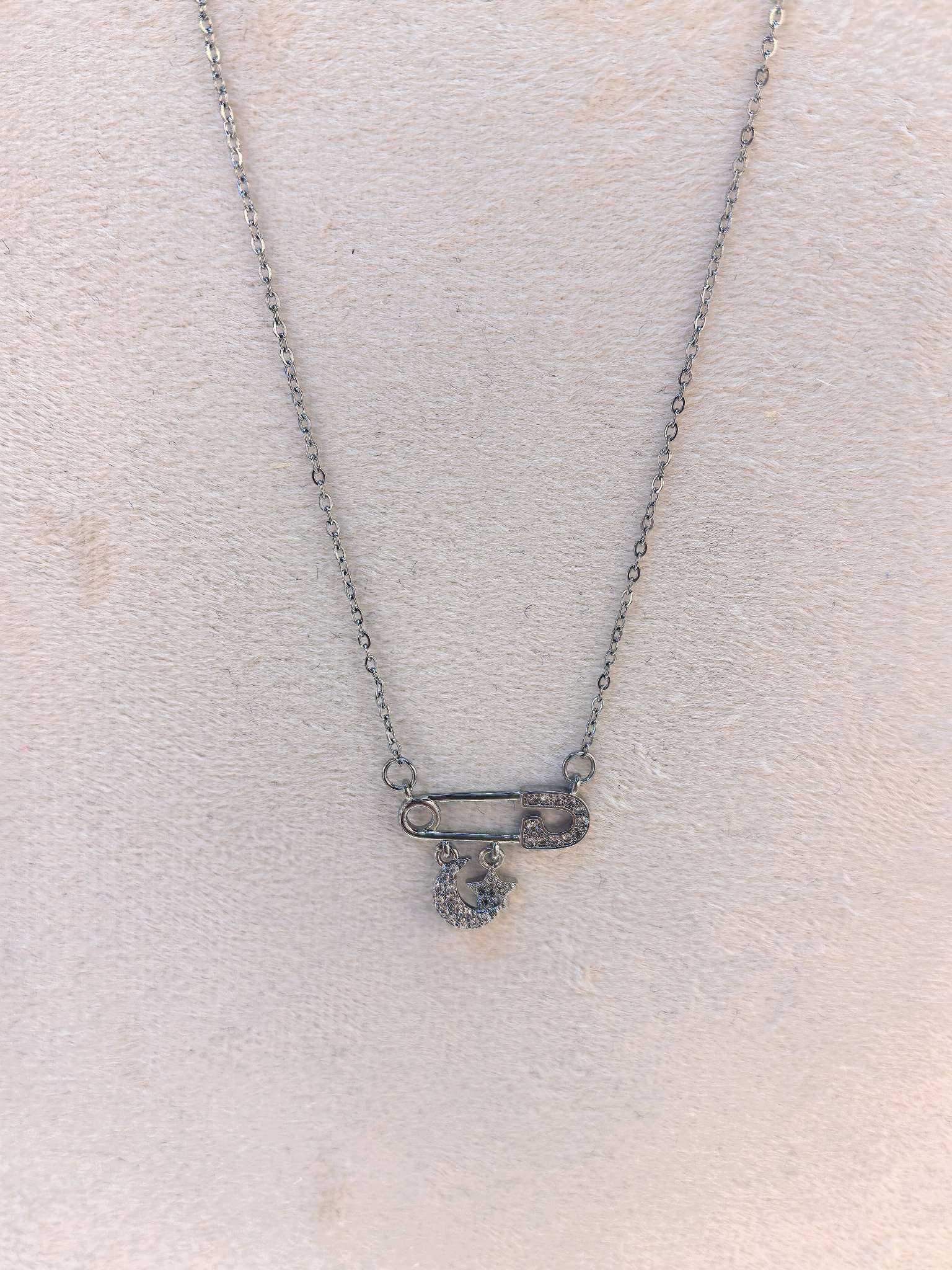 Silver safety pin necklace with diamond-encrusted moon and star pendant Item Picture