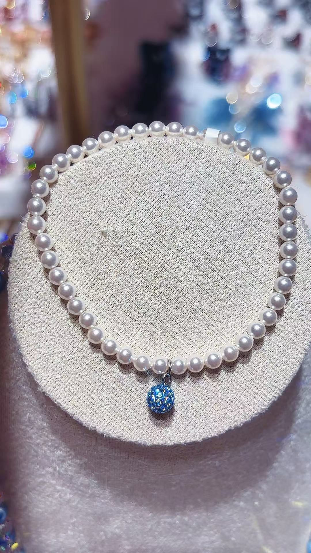 A custom-made irregular and versatile snake-shaped bracelet for women with a white pearl bracelet and a blue crystal ball pendant