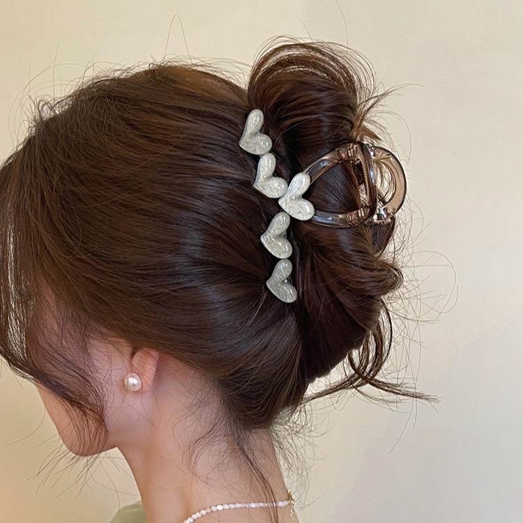 The sweet and heart-shaped flower hairpin is a medium-sized, transparent grey claw clip at the back of the female head, exuding a sense of elegance and sophistication. It is a shark clip headpiece undefined