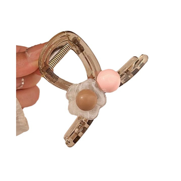 The sweet and heart-shaped flower hairpin is a medium-sized, transparent grey claw clip at the back of the female head, exuding a sense of elegance and sophistication. It is a shark clip headpiece Item Picture