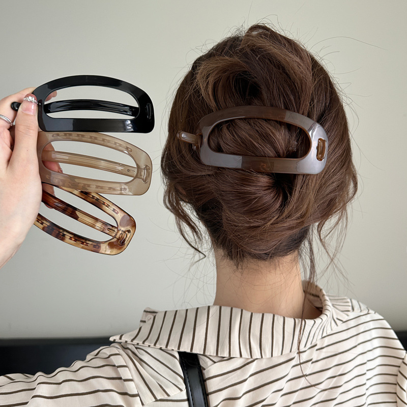 The simple and elegant oval hair clip at the back of the female head exudes a sense of sophistication. The one-piece twist clip is a large bun with a generous amount of hair and a headwear clip full image