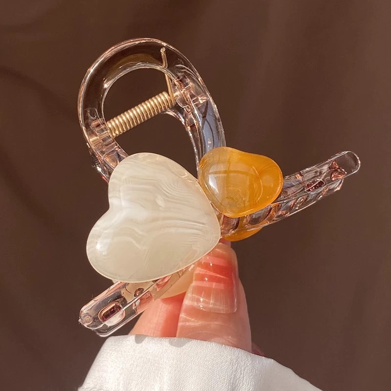 The sweet and heart-shaped flower hairpin is a medium-sized, transparent grey claw clip at the back of the female head, exuding a sense of elegance and sophistication. It is a shark clip headpiece undefined