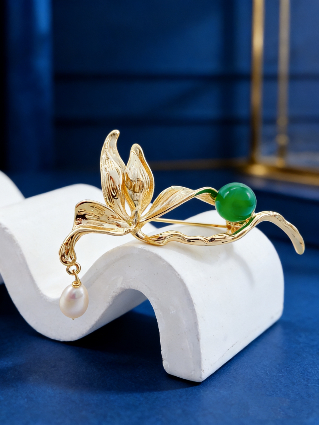 A golden leaf-shaped brooch set with green round beads, white pearls and a fashionable pin in a blue velvet box details Picture