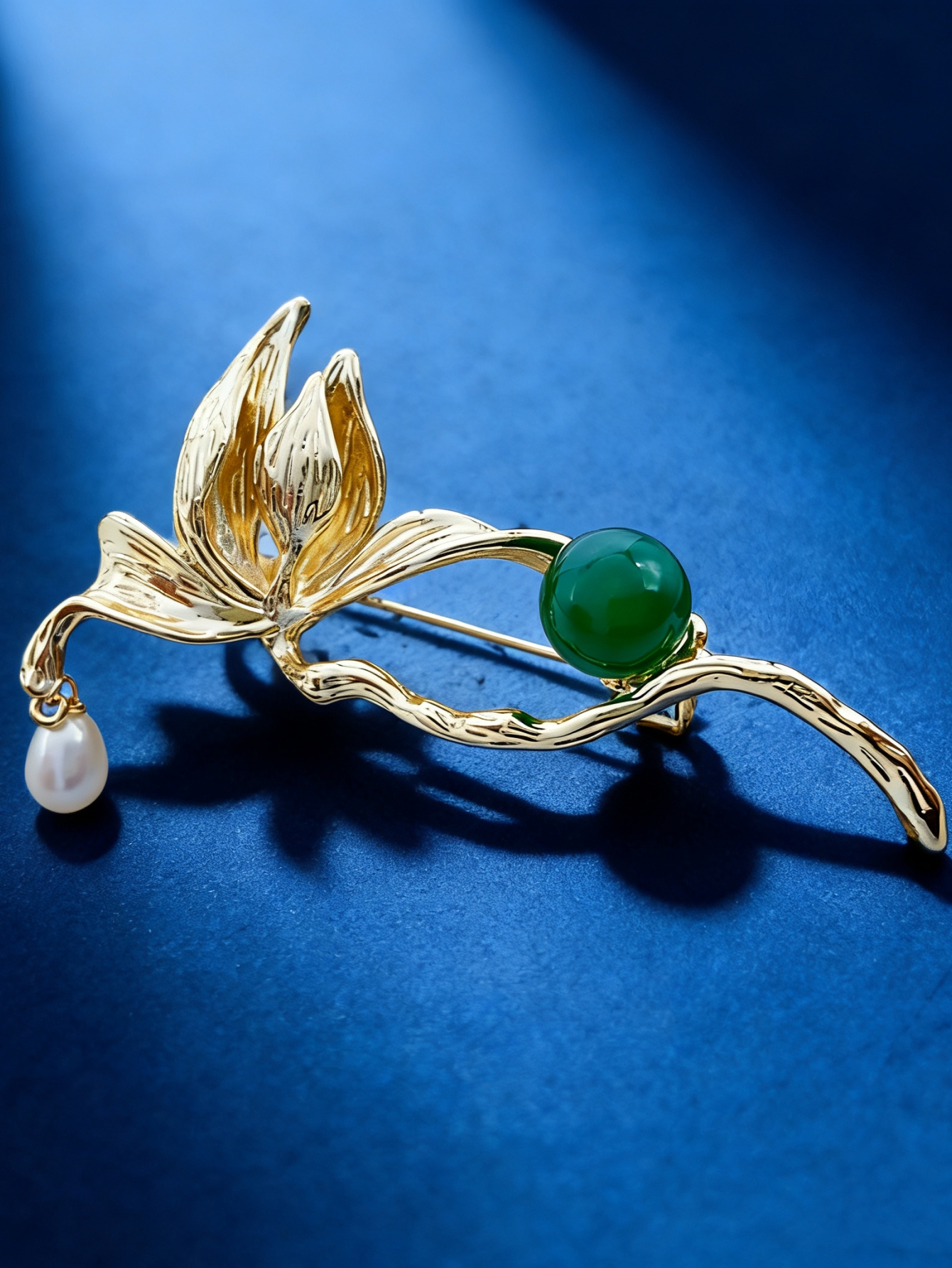 A golden leaf-shaped brooch set with green round beads, white pearls and a fashionable pin in a blue velvet box Specification image