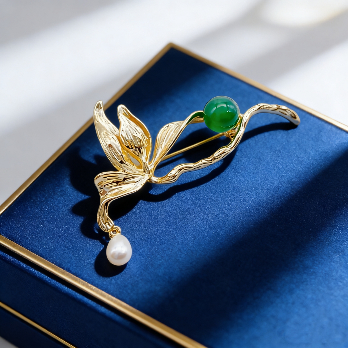 A golden leaf-shaped brooch set with green round beads, white pearls and a fashionable pin in a blue velvet box pic 2