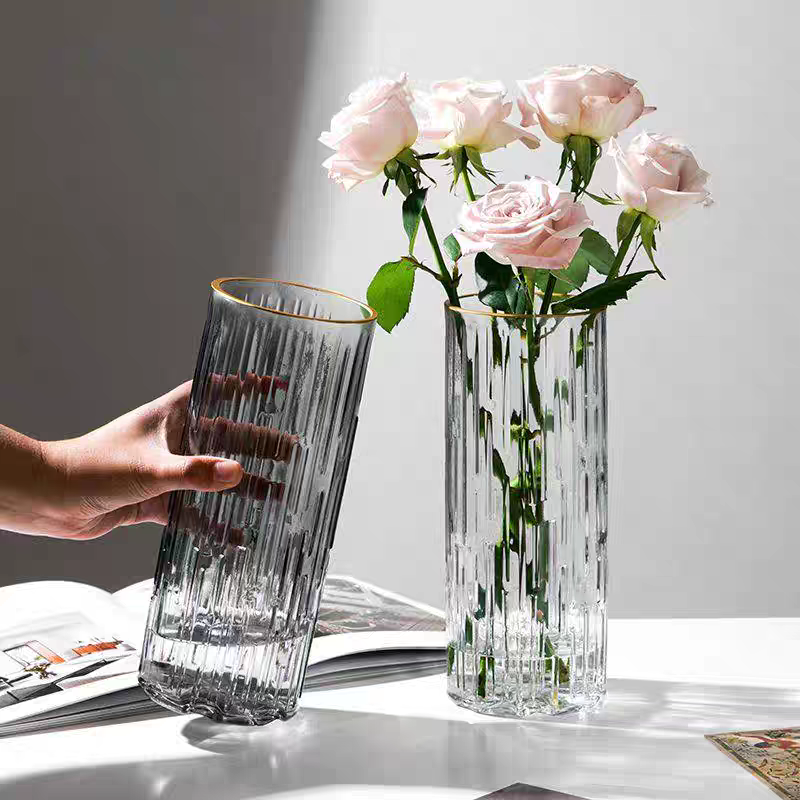 A light luxury glass vase with 25 vertical stripes in gold, simple and transparent, exuding a sense of sophistication. It is an ins feng shui lily hydroponic fresh flower arrangement for the living room